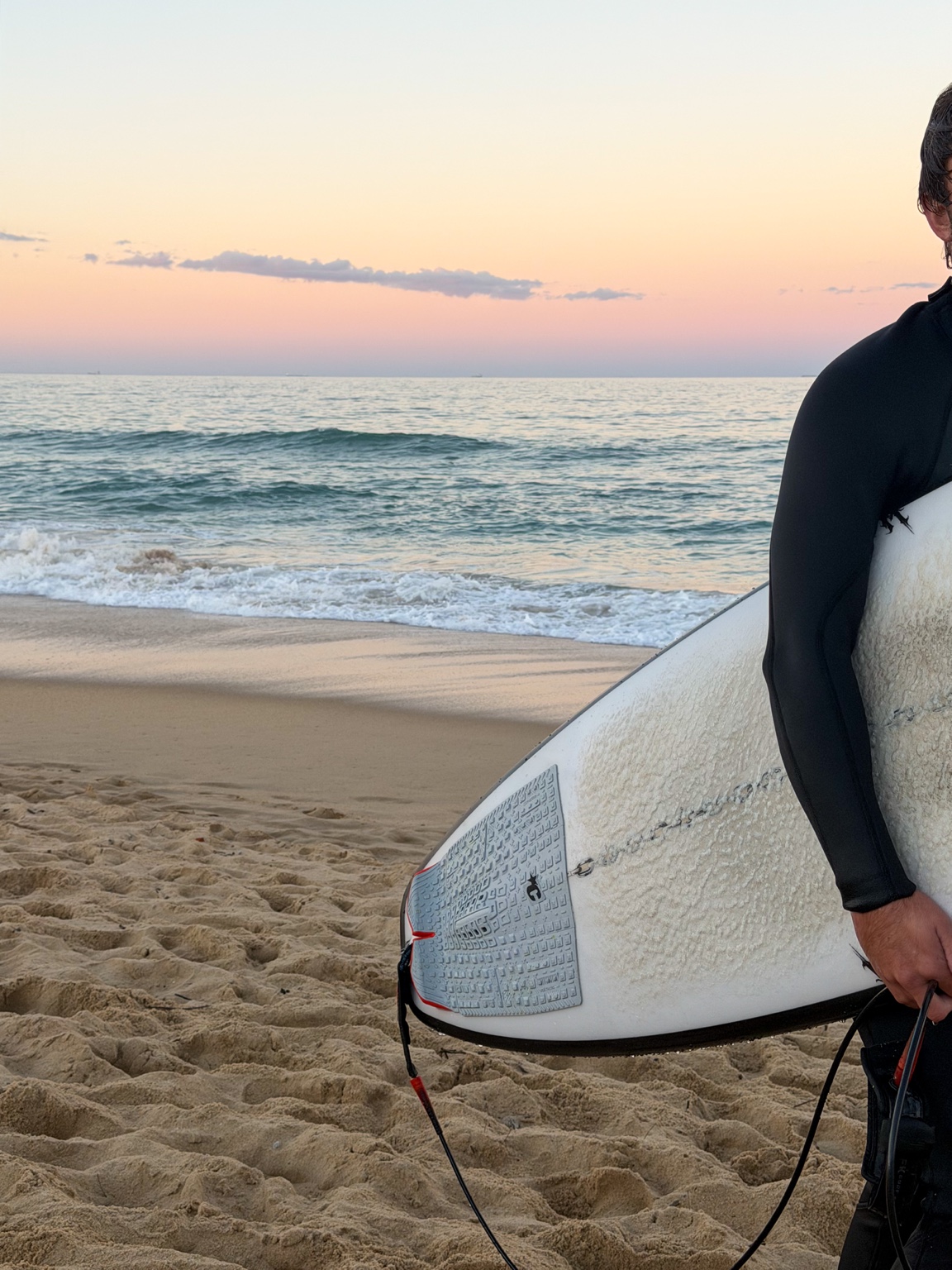 Surfer carrying a surfboard on the beach at sunset